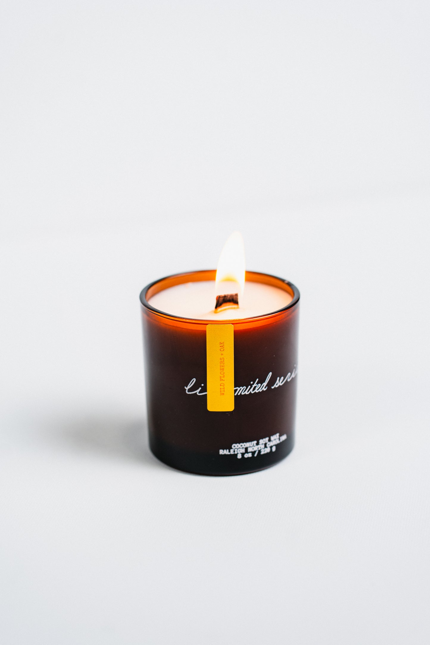 Candle in a black container with a yellow label on a white background